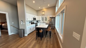 A modern kitchen with a central island, white cabinetry, and stainless steel appliances. - Lake View-5 Bedroom-Hot Tub-Kings-EV Charger, Dam View Vista-Lake View-King Beds With Luxury Linens-... (Oakland)