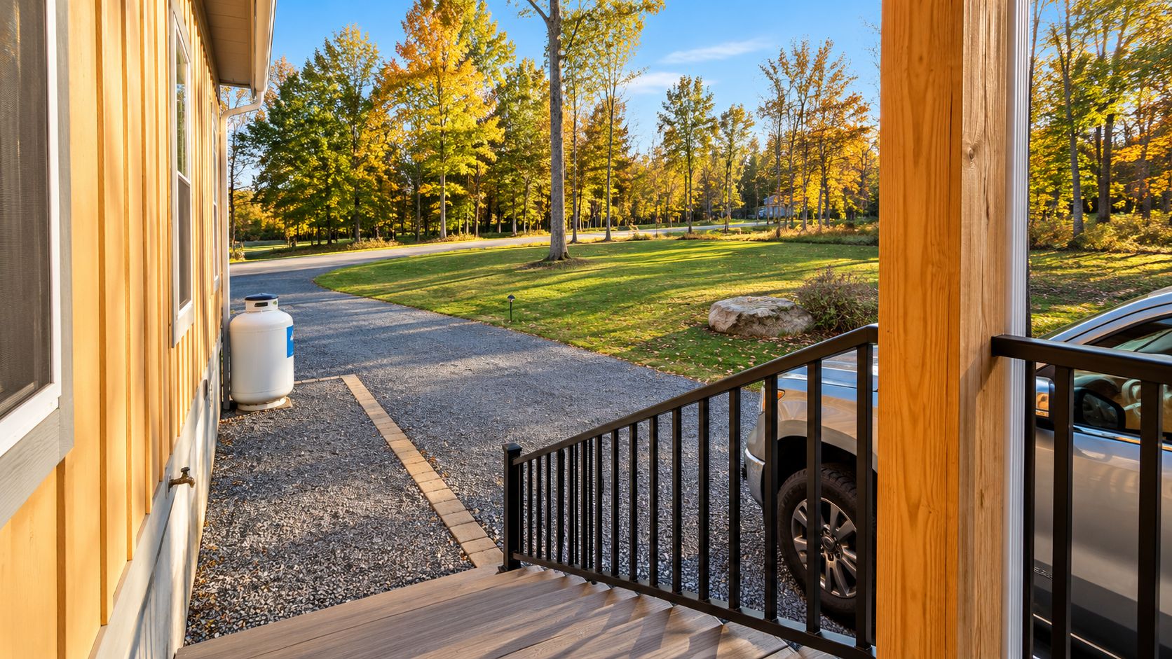 A wooden exterior with a gravel driveway leading to a car parked in the driveway.