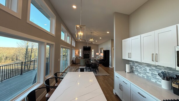 A spacious kitchen with a large island, white cabinets, and a stone backsplash. - Lake View-5 Bedroom-Hot Tub-Kings-EV Charger, Dam View Vista-Lake View-King Beds With Luxury Linens-... (Oakland)