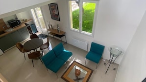 A spacious living area with a kitchen, a dining table, and two blue sofas. - Le Laurier Blanc is 10 minutes from Parc Caillebotte, with its terrace for aperitifs. (Yerres)