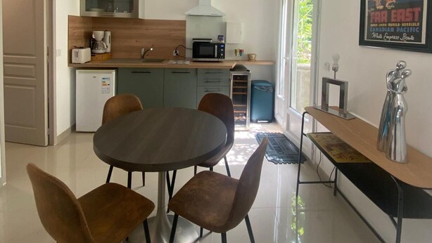 A modern kitchen with a dining area, a refrigerator, a microwave, and a coffee maker. - Le Laurier Blanc is 10 minutes from Parc Caillebotte, with its terrace for aperitifs. (Yerres)