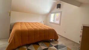 A bedroom with a bed, a geometric-patterned rug, a window with a view, and a door. - Le Laurier Blanc is 10 minutes from Parc Caillebotte, with its terrace for aperitifs. (Yerres)