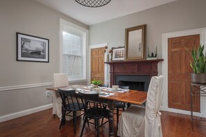 A dining room with a wooden table, black chairs, a fireplace, and a framed picture on the wall. - Step into History: Charming Fells Point Retreat (Baltimore)