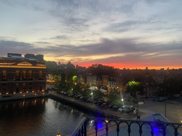 A cityscape with a river, buildings, and a sunset. - Step into History: Charming Fells Point Retreat (Baltimore)