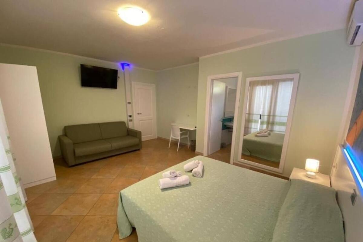 Een slaapkamer met een bed, een bank, een bureau en een televisie.
