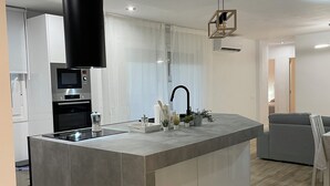 A modern kitchen with a central island, stainless steel appliances, and a black range hood. - Spacious 4-bedroom apartment with WiFi, AC in gorgeous Fuengirola (Fuengirola)