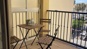 A balcony with a wooden table and chairs, a potted plant, and a view of the street below. - Spacious 4-bedroom apartment with WiFi, AC in gorgeous Fuengirola (Fuengirola)