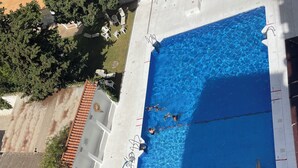 An aerial view of a swimming pool with multiple lanes, surrounded by white lounge chairs and a covered seating area. - Spacious 4-bedroom apartment with WiFi, AC in gorgeous Fuengirola (Fuengirola)