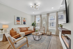 A modern living room with a sofa, armchairs, a coffee table, and a fireplace. - Modern World Cup 5BR Near Downtown  Parking, Backyard & Walk to Train (Boston)