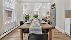Una cucina moderna con frigorifero, un tavolo da pranzo per sei persone e un'ampia finestra con tende.