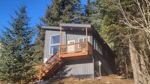 A two-story cabin with a wooden deck and stairs leading to a balcony.