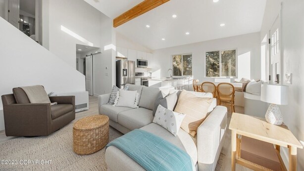 A spacious living area with a sofa, a dining table, and a kitchen in the background.