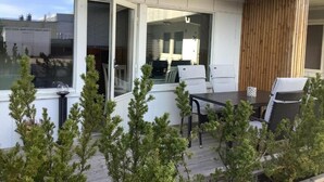 Un espacio al aire libre moderno con una mesa y sillas, rodeado de árboles pequeños.