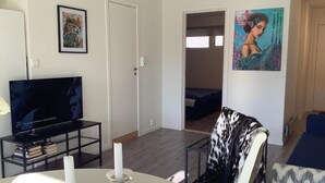Una sala de estar con televisor, una mesa de comedor con velas y obras de arte en las paredes.