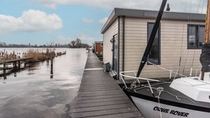 A dock with a boat named "OLWE ROVER" and a small building adjacent to it. - Spacious 120m2 Watervilla With Sauna Near Amsterdam And Schiphol. (Aalsmeer)
