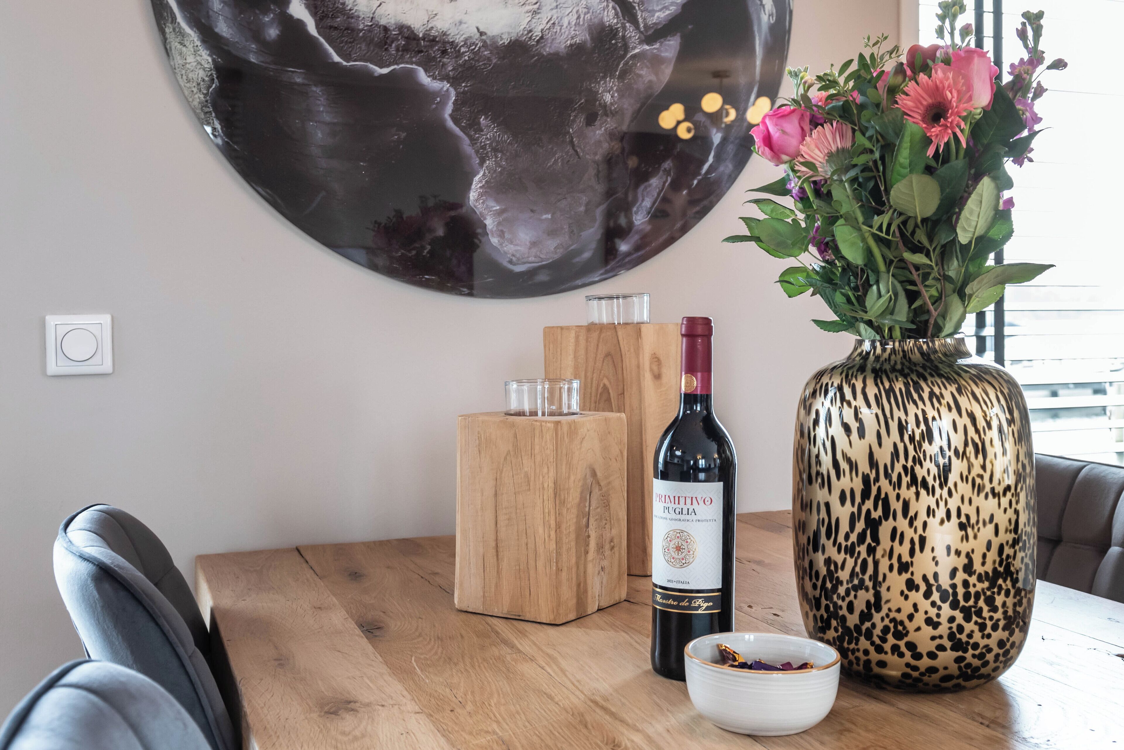 Una mesa de madera con una botella de vino, un florero con flores y un candelabro.
