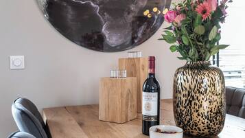Una mesa de madera con una botella de vino, un florero con flores y un candelabro.