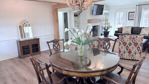 Een eetruimte met een ronde glazen tafel, houten stoelen en een kroonluchter.