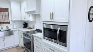 Een moderne keuken met witte kastjes, roestvrijstalen apparatuur en gouden handgrepen.