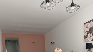 Un coin repas avec une table en marbre blanc, des chaises noires, un vase avec des fleurs et, au fond, un canapé gris.