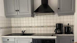 Une cuisine avec des meubles de couleur grise, une hotte noire, une machine à café et un lave-vaisselle.