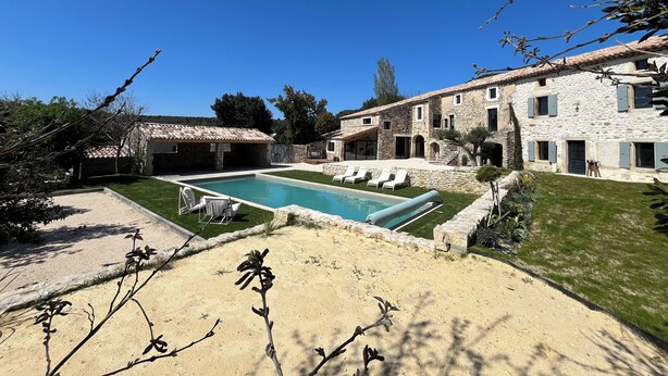 Un bâtiment en pierre doté d’une piscine, d’un espace extérieur aménagé et d’une pelouse bien entretenue.
