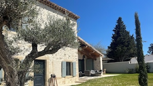 Une maison en pierre dotée d’un patio couvert, d’un espace salon extérieur et d’une pelouse bien entretenue.