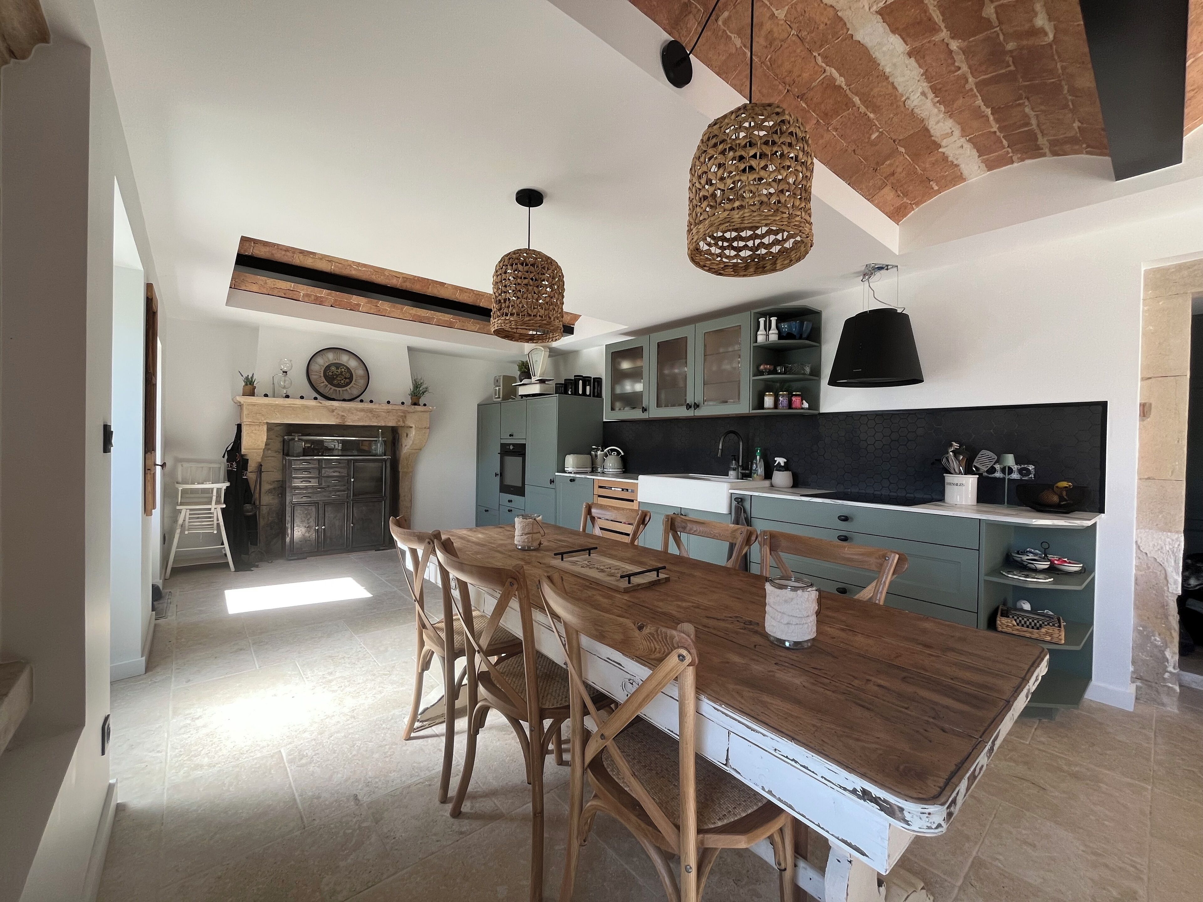 Une cuisine moderne avec une table et des chaises en bois, un plafond en briques et un luminaire suspendu.
