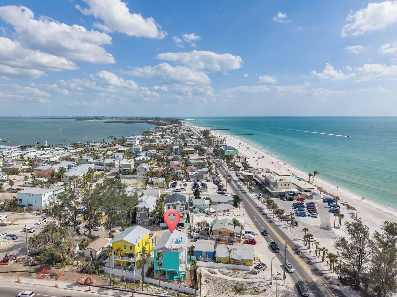 An aerial view of a coastal town with a beach, roads, and buildings.