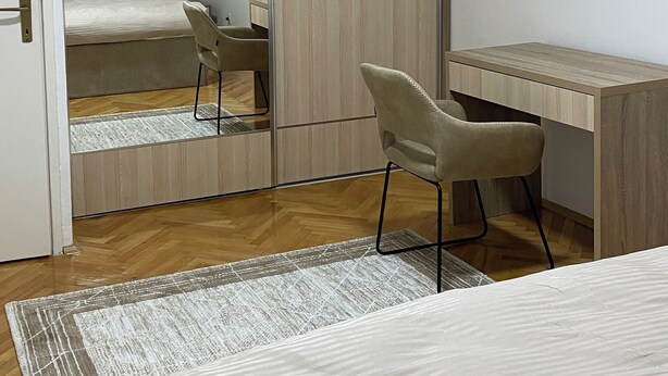 A bedroom with a bed, a desk, a chair, a wardrobe, and a mirror. - Modern City Apartment (Bitola)
