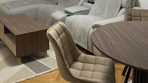 A modern living room with a sectional sofa, a round coffee table, and two armchairs. - Modern City Apartment (Bitola)