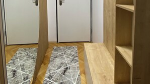 A room with two white doors, a wooden wardrobe, a marble-patterned rug, and a wooden floor. - Modern City Apartment (Bitola)