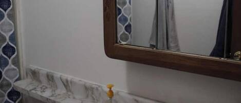 A bathroom with a marble sink, a mirror, and a shower curtain.