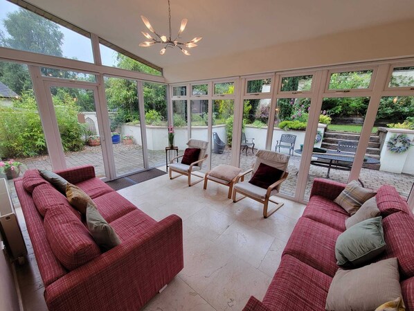 A spacious patio with a red sofa set, a wooden chair, and a table. - A House in Avoca - The Garden of Ireland (Avoca)