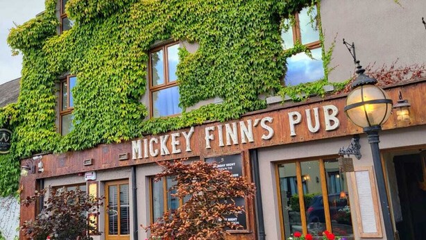 Mickey Finn's Pub with ivy-covered walls, outdoor seating, and a rustic sign.