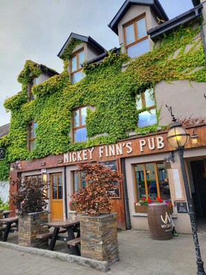 Le pub Mickey Finn's, avec ses murs couverts de lierre, ses tables en plein air et son enseigne rustique.