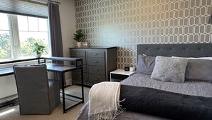 Un dormitorio con cama, escritorio, silla, cómoda y ventana.