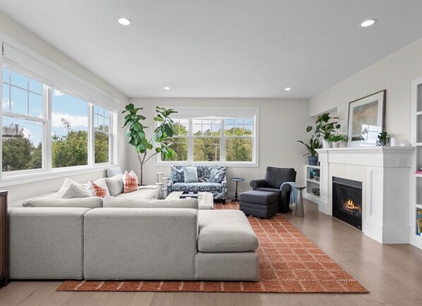 A modern living room with a sectional sofa, a patterned armchair, and a fireplace.