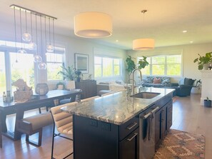 A modern kitchen with a central island, pendant lights, and a dining area with a bench.