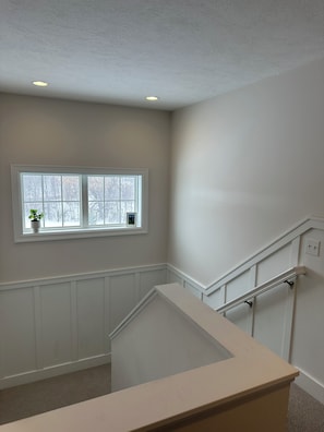 A staircase with a handrail, a window with a view of trees, and a ceiling with recessed lighting. - Clean, Spacious 5BR 3.5 bath home conveniently located in charming Traverse City (Traverse City)