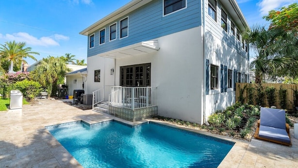 Ein zweistöckiges Haus mit Swimmingpool, überdachter Terrasse und eingezäunter Garten.
