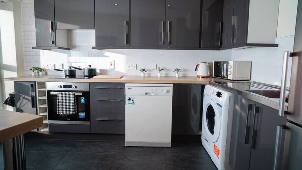 Una cocina moderna con electrodomésticos de acero inoxidable, lavavajillas, lavadora y microondas.