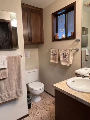 A bathroom with a toilet, sink, and wooden cabinets. - 1 Bedroom Retro Riverside Home with view ! (Sultan)