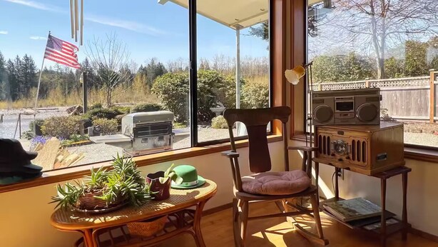 A room with large windows, a wooden table with plants, a chair, and a vintage radio. - 1 Bedroom Retro Riverside Home with view ! (Sultan)