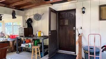A rustic kitchen with a wooden ceiling, a black door, and a small stool.