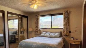 A bedroom with a bed, a nightstand, a lamp, a ceiling fan, and a window with curtains. - 1 Bedroom Retro Riverside Home with view ! (Sultan)