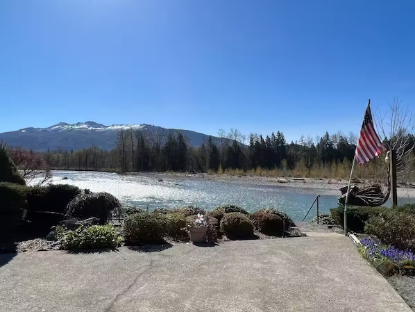 A riverside view with a mountain in the background, a flag, and some bushes. - 1 Bedroom Retro Riverside Home with view ! (Sultan)