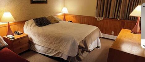 A hotel room with a bed, two bedside tables with lamps, a painting on the wall, and a window with curtains.