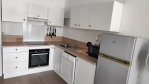 Una cocina moderna con armarios blancos, encimera de madera, horno empotrado, lavavajillas, fregadero y refrigerador.