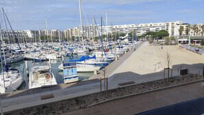 Un puerto deportivo con numerosas embarcaciones amarradas, una playa de arena y una hilera de edificios al fondo.